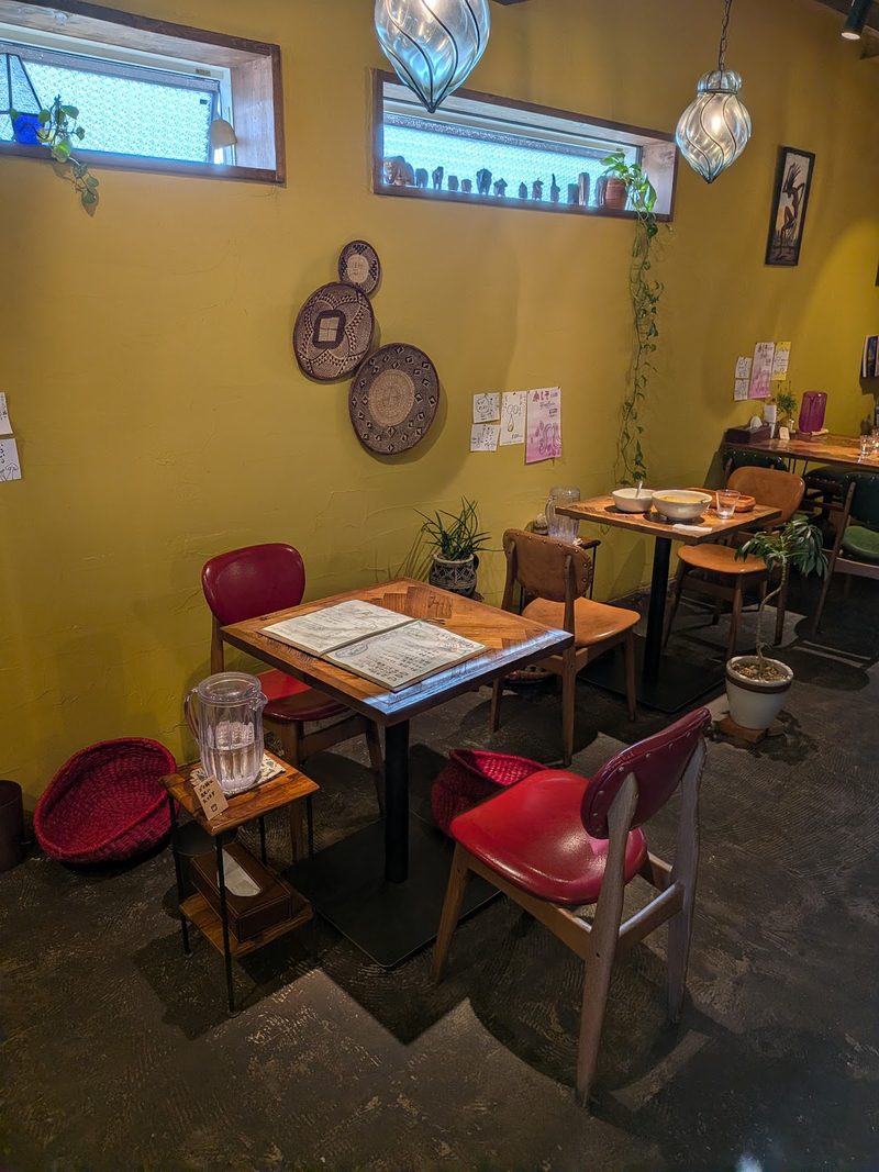 からし色の壁と赤い椅子、木のテーブルが並ぶ店内